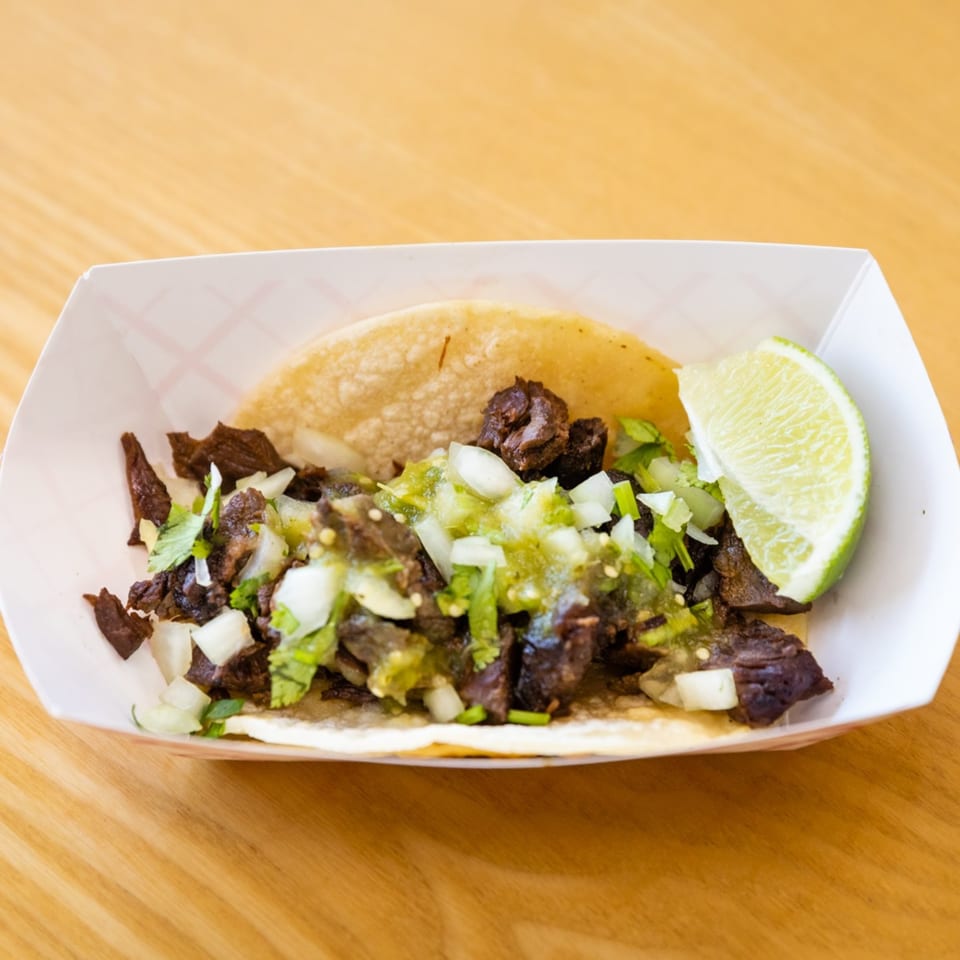 A Blue Tortilla Fresh Mexican Grille carne asada taco with salsa verde, onions, and cilantro.