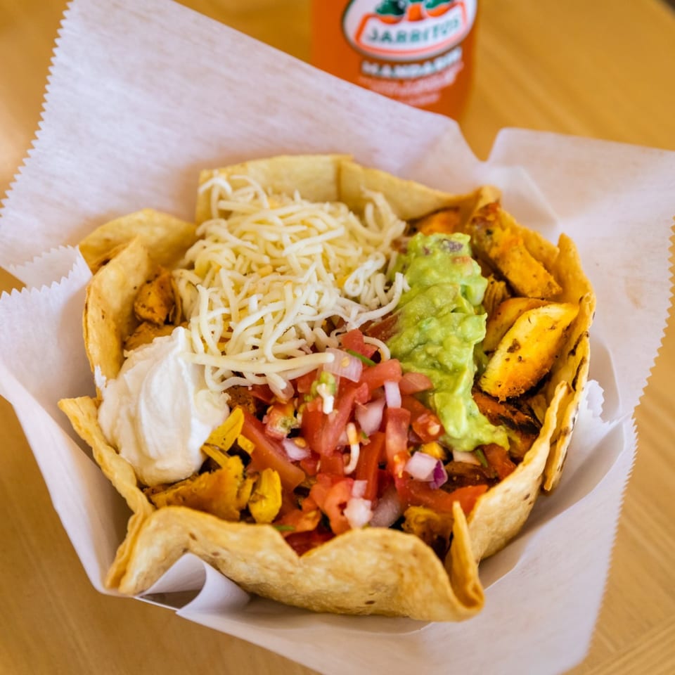 A Blue Tortilla Fresh Mexican Grille taco salad in a crispy shell with chicken, guacamole, and sour cream.