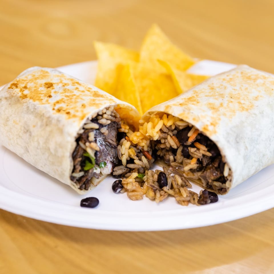 A Blue Tortilla burrito, cut in half, revealing rice and black beans, with tortilla chips.