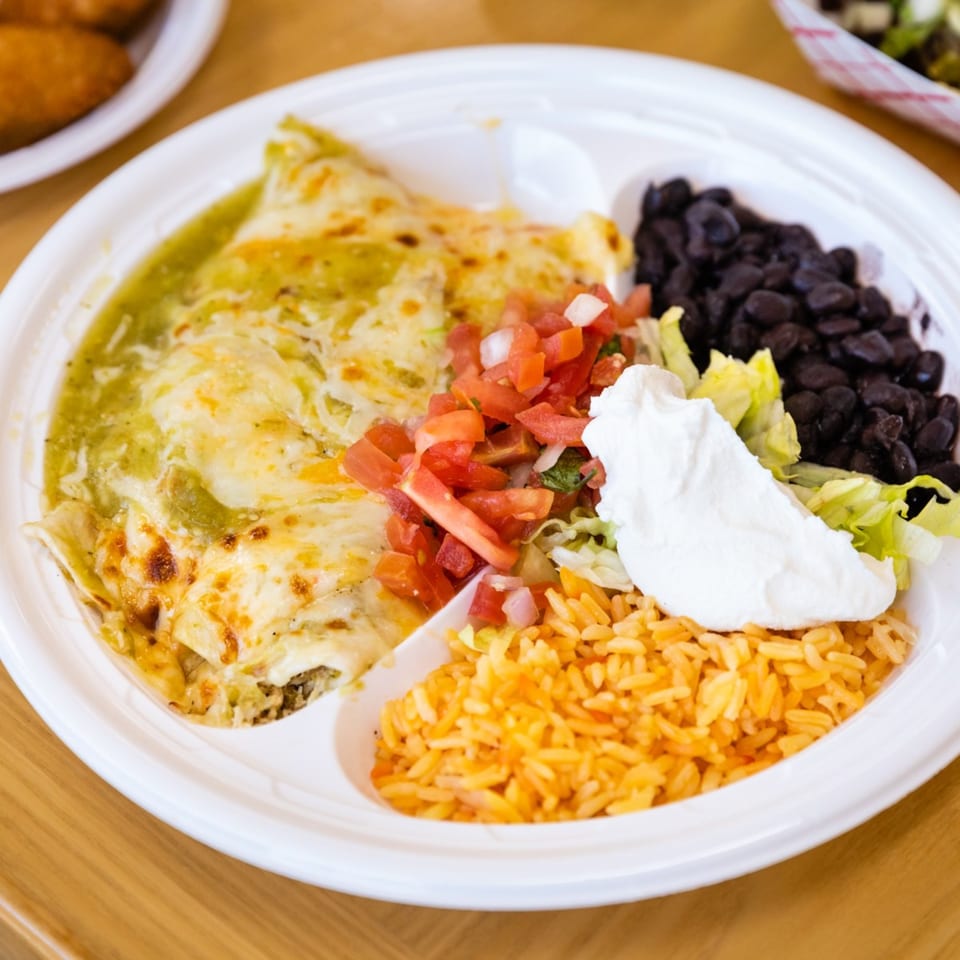 A Blue Tortilla Fresh Mexican Grille enchilada plate with rice, black beans, pico de gallo, and sour cream.